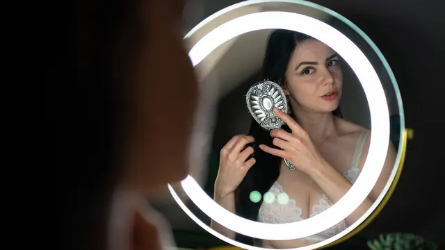 Vrouw die haar haar borstelt, gefotografeerd via een ronde spiegel