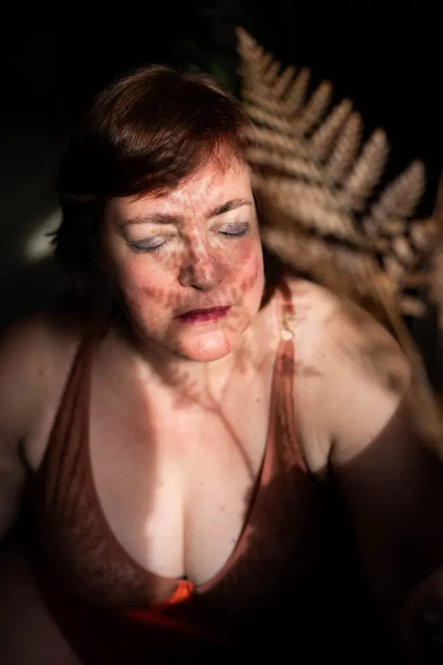 Boudoirportret van een vrouw van middelbare leeftijd met de schaduw van een varen over haar gezicht