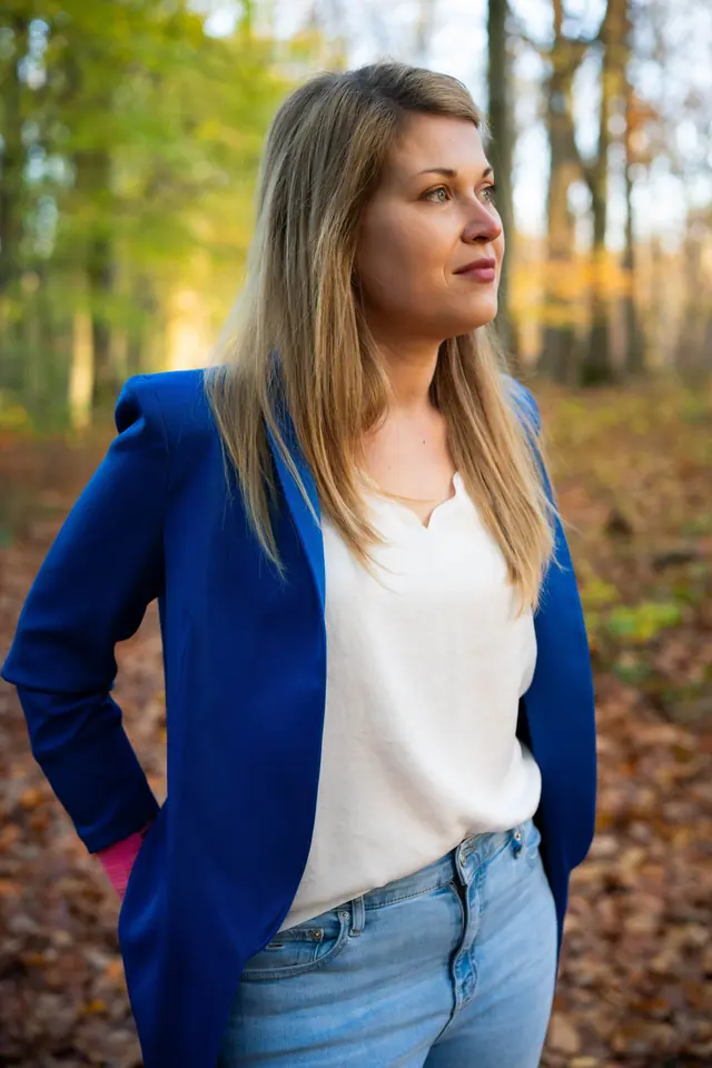Vrouw in een blauwe blazer in een herfstbos