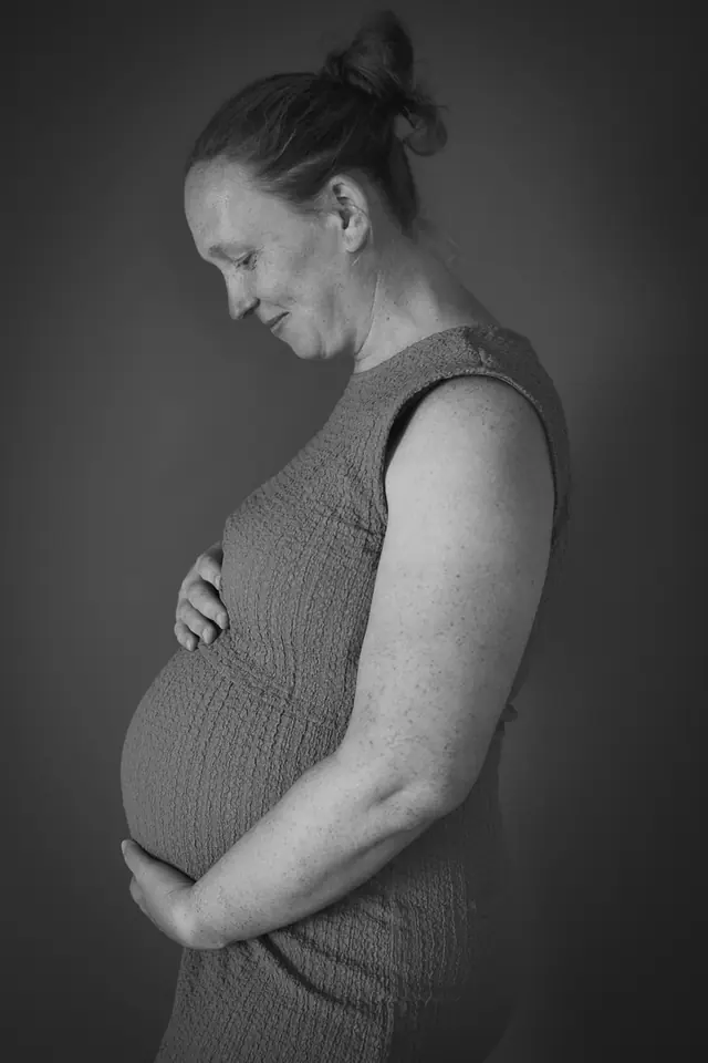 Zwart-wit profielportret van een zwangere vrouw die naar haar buik kijkt